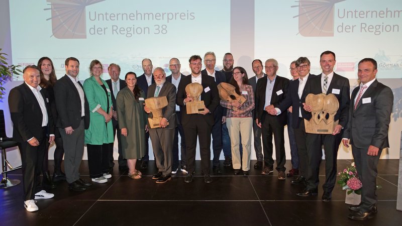 Gruppe von Personen posiert mit Trophäen bei der Verleihung des Unternehmerpreises der Region 38.