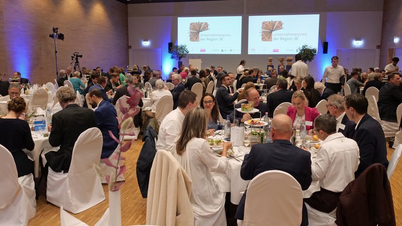 Eine voll besetzte Veranstaltungshalle mit Gästen beim Abendessen während einer Preisverleihung.