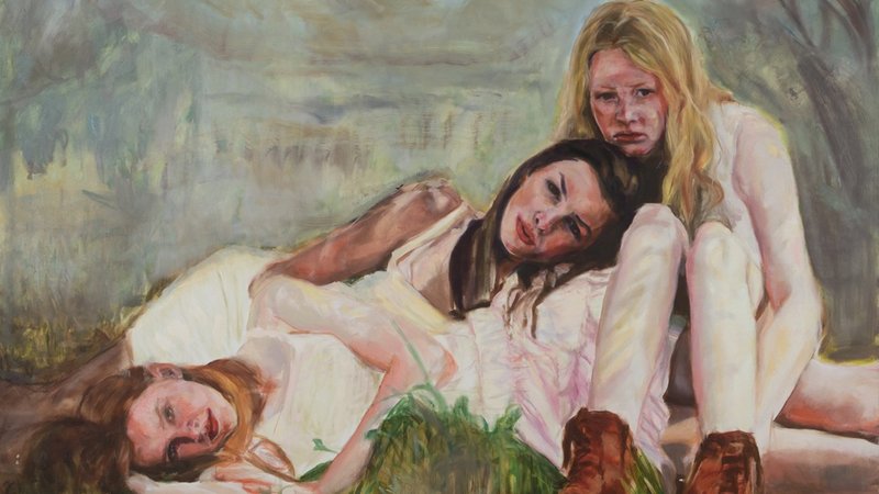 Drei Frauen in weißen Kleidern liegen auf dem Boden, mit ausdrucksvollen Gesichtern in einer melancholischen Atmosphäre.