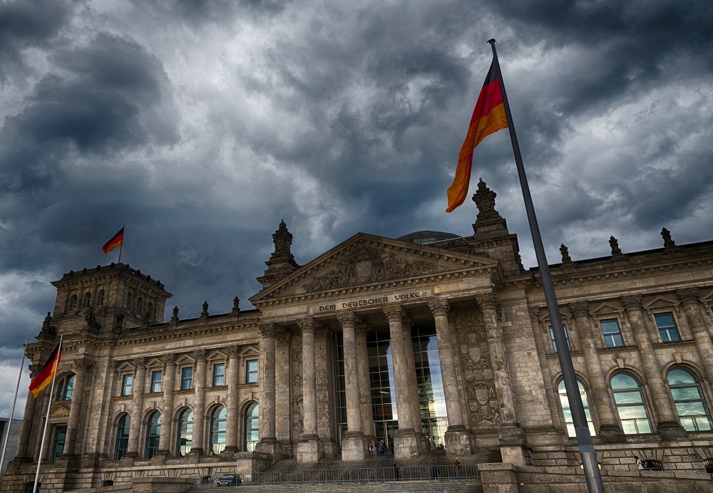 Dramatischer Himmel über dem Reichstagsgebäude in Berlin mit wehenden deutschen Flaggen.